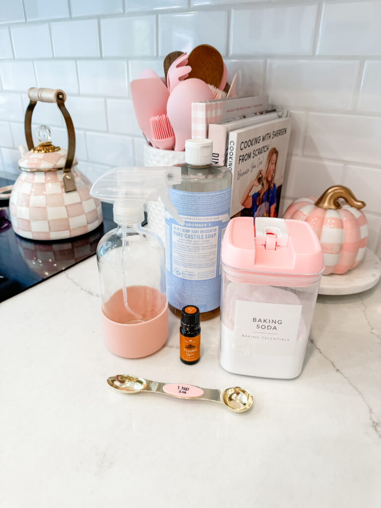 Ingredients for a DIY Pumpkin Spice Cleaning Spray all set out on a marble countertop.