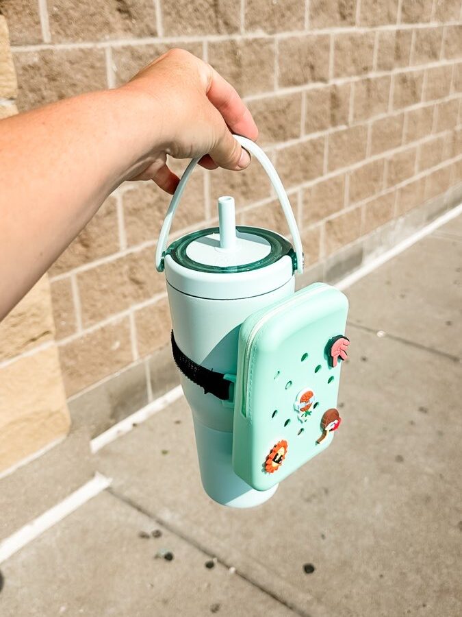 Photo of a practical water bottle pouch with multiple compartments, designed to hold essentials like headphones, keys, and a phone. The pouch is attached to a water bottle, showcasing its convenience for gym sessions or on-the-go activities.