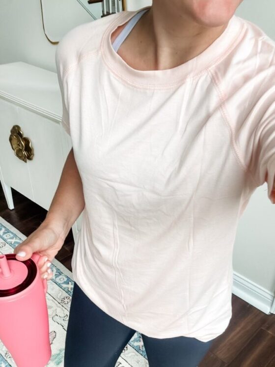 Photo of a longline soft t-shirt in a neutral color, styled on a hanger. The shirt features an oversized fit with a tailored design that drapes slightly longer in the back, ideal for comfortable coverage during workouts or casual outings.