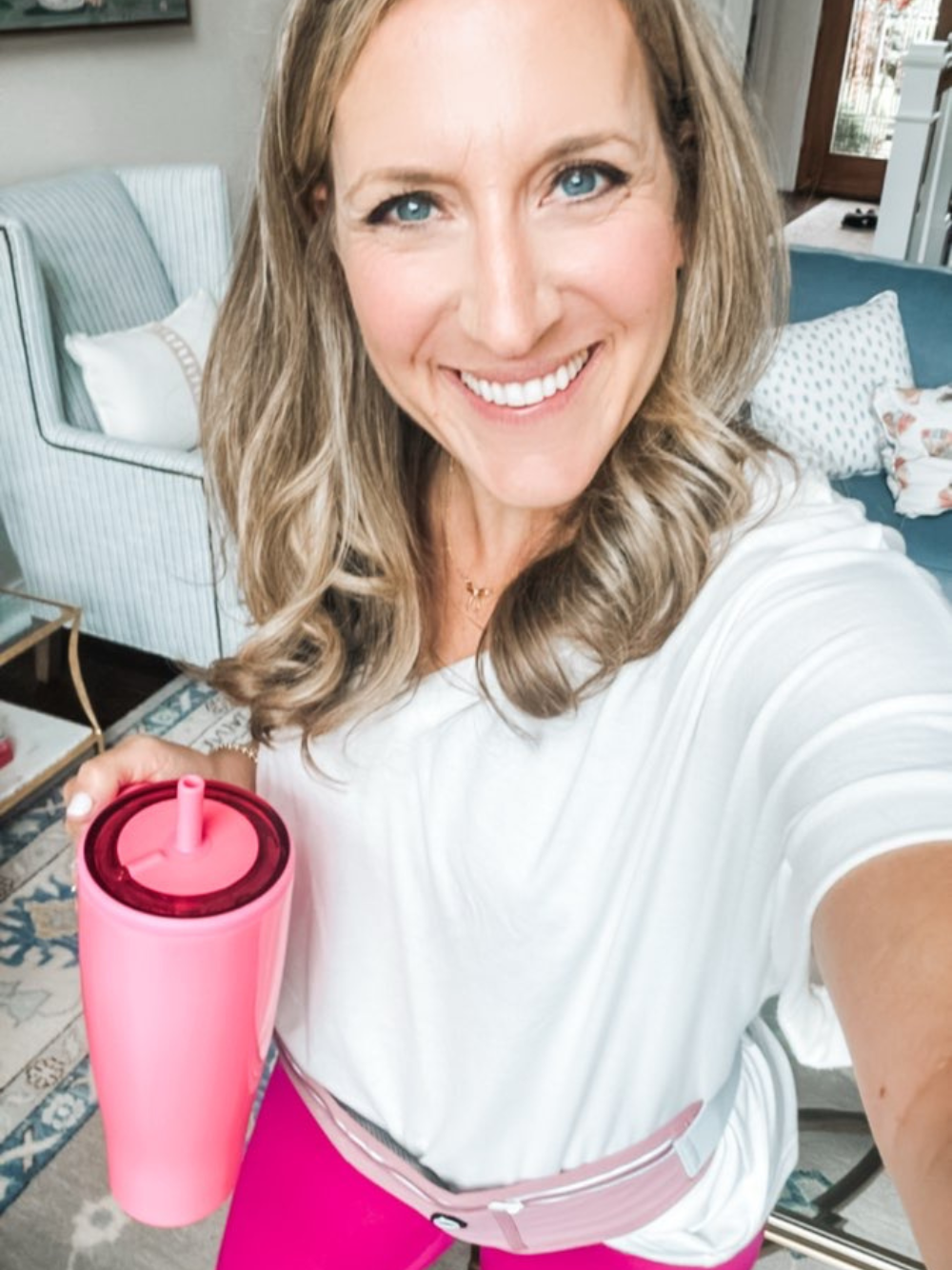 Photo of a casual workout outfit featuring a white oversized tee paired with pink leggings. Accessories include a bright pink Brumate water bottle and a slim workout belt, combining style and functionality for an active day.
